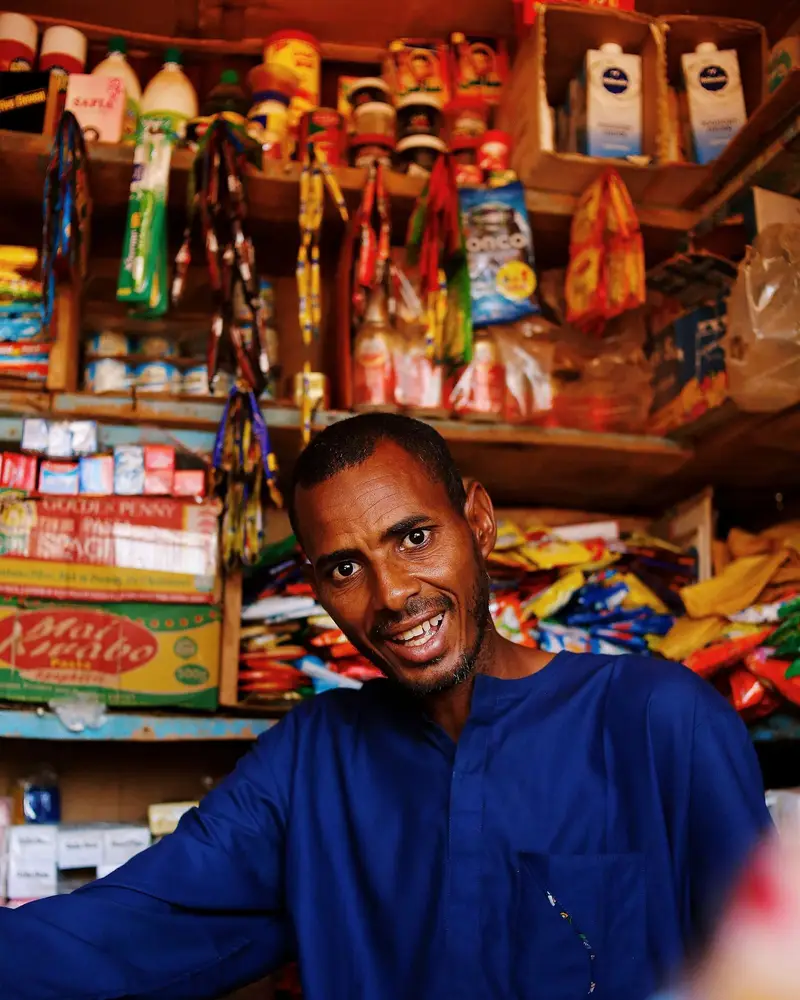 Comerciante sorridente ao balcão da sua mercearia.